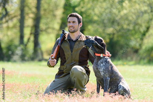 huntsman with gun kneeling by his dog photo