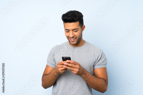 Young handsome man over isolated background sending a message or email with the mobile