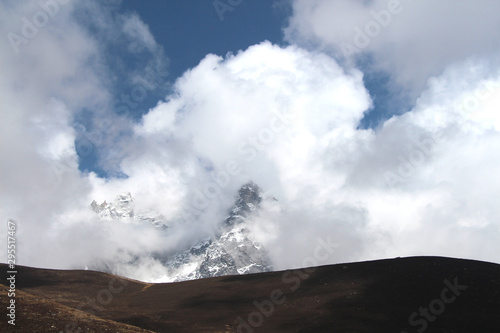 Kyajo Ri mountain peak is visible through dense white clouds in Himalayas in Sagarmatha national park in Nepal near Lunden village. On the way to Everest base camp through Gokyo lakes.