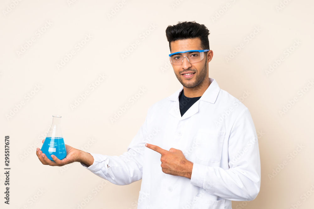 Young handsome man over isolated background with a scientific test tube and pointing it Young handsome man over isolated background with a scientific test tube and pointing it