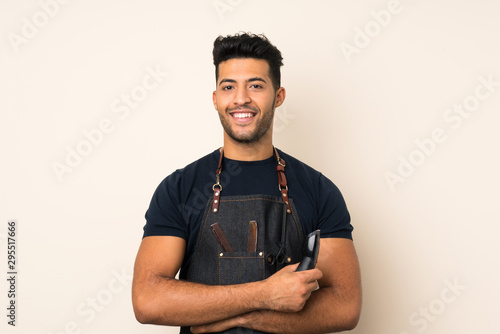 Young handsome man over isolated background with hairdresser or barber dress and holding hair cutting machine