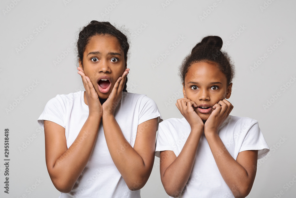 Shocked emotional african american sisters on grey background Shocked emotional african american sisters on grey background