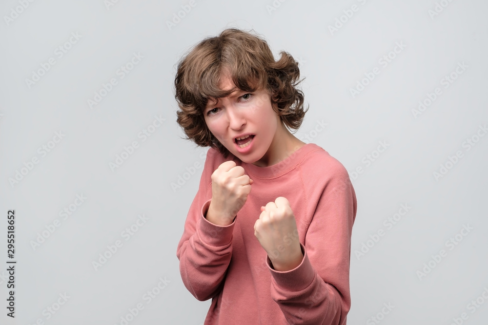 Strong woman keeping fists clenched in front of her defending herself from offence. Studio shot Strong woman keeping fists clenched in front of her defending herself from offence. Studio shot