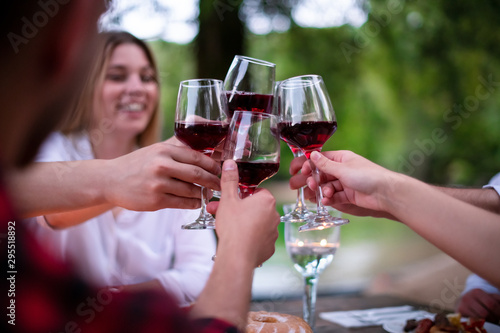 happy friends toasting red wine glass during french dinner party outdoor