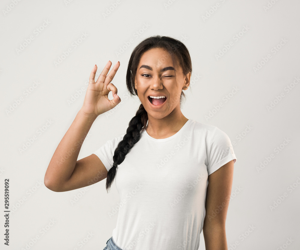 Happy girl gesturing OK sign and winking Happy girl gesturing OK sign and winking