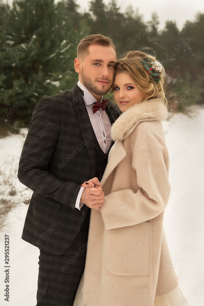 the couple is hugging and close to the kiss, holding hands, a bouquet in their hands. A suit with a butterfly and a coat with a dress. The bride and the groom the couple is hugging and close to the kiss, holding hands, a bouquet in their hands. A suit with a butterfly and a coat with a dress. The bride and the groom