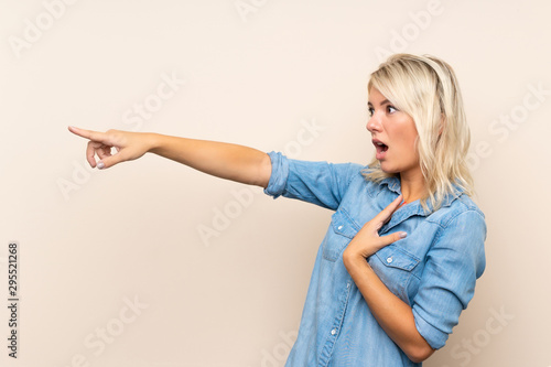 Young blonde woman over isolated background pointing finger to the side