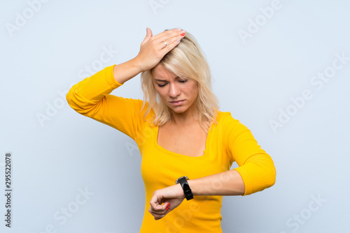 Young blonde woman over isolated background with wrist watch and surprised