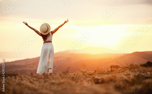 Happy woman standing with her back on sunset in nature .