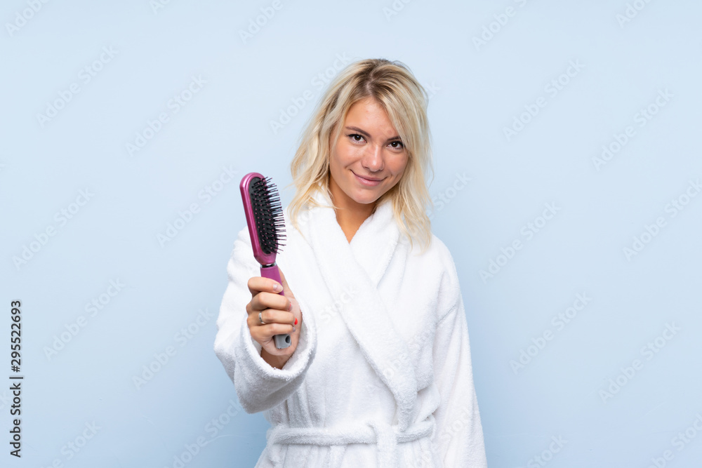 Young woman in a bathrobe with hair comb with happy expression Young woman in a bathrobe with hair comb with happy expression