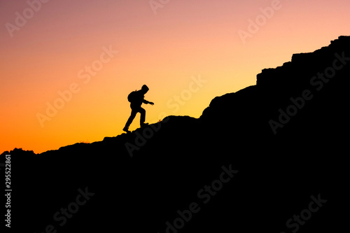 photo in a dark key of a man climbing a mountain