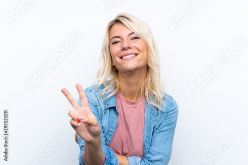 Young blonde woman over isolated white background smiling and showing victory sign