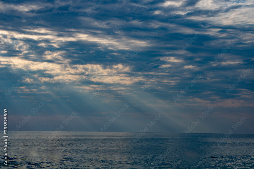 The rays of the summer sun make their way through the thick clouds over the Black Sea in the evening