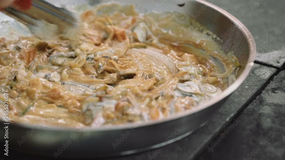 Stirring mushrooms, meat, seafood and butter in a frying wok pan closeup Stirring mushrooms, meat, seafood and butter in a frying wok pan closeup