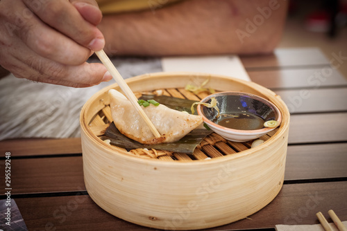 Thai food. mixed chicken, shrimp and vegetable gyozas in a Thai steamer with soy sauce in a black bowl photo