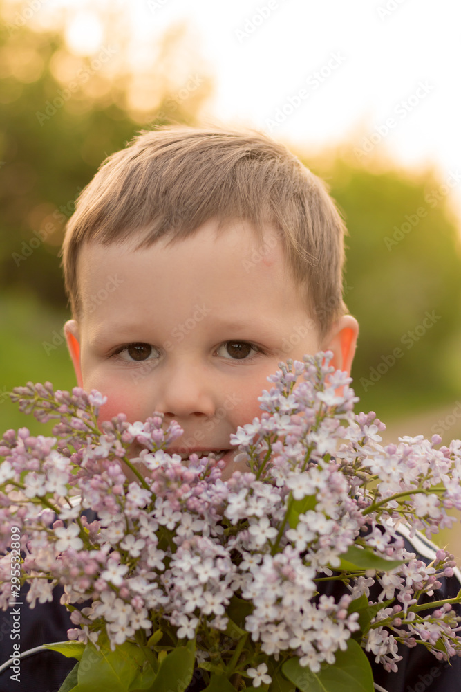portrait of a boy with lilac. bouquet of purple lilac in children's hands. hands holding a purple lilac flowers bouquet in meadow. portrait of a boy with lilac. bouquet of purple lilac in children's hands. hands holding a purple lilac flowers bouquet in meadow.