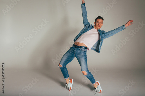 Fototapeta Naklejka Na Ścianę i Meble -  shot of mad, crazy, cheerful, successful, lucky guy in casual outfit, jeans, jumping with hands up,triumphant, gesturing against white background