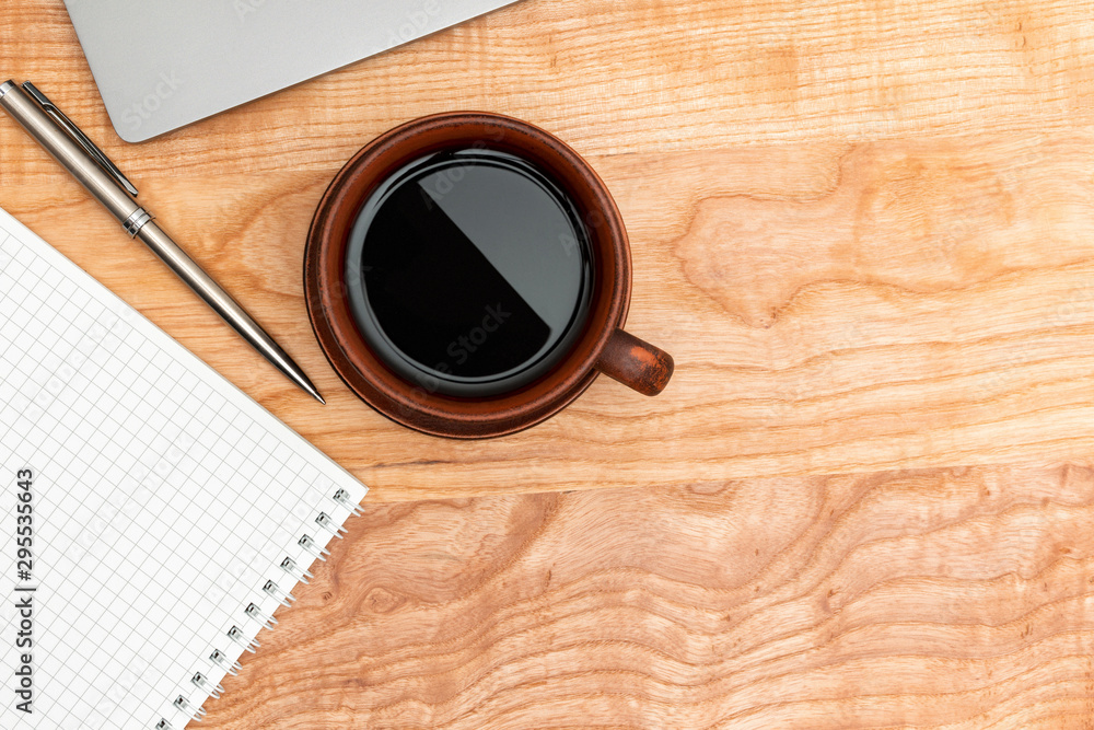 Work wooden office table with laptop, coffee cup, notepad and pen, top view Work wooden office table with laptop, coffee cup, notepad and pen, top view
