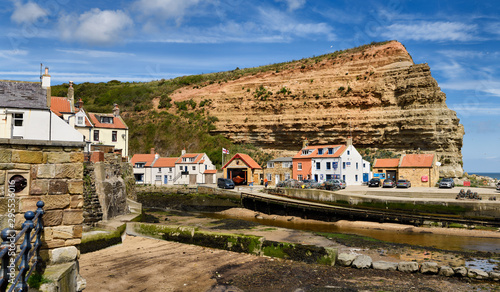 Red cliff of Jurassic strata at the mouth of Staithes Beck emptying into the North Sea at Staithes harbour North York Moors National Park England