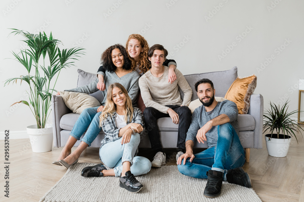 Happy young casual couple and their friends sitting in front of camera Happy young casual couple and their friends sitting in front of camera