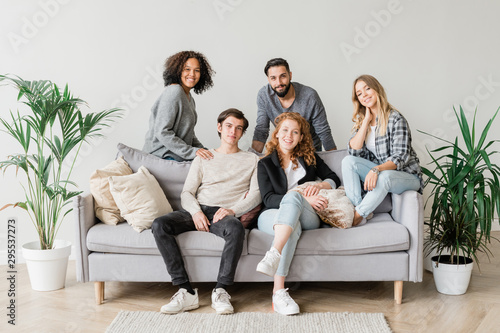Joyful intercultural teenagers in casualwear relaxing on sofa together