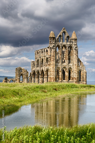 Gothic ruins of 13th Century Whitby Abbey on the North Sea reflected in the Abbey Pond Whitby North York Moors National Park England