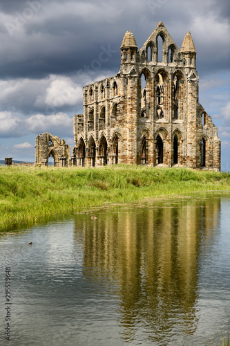 Gothic ruin of 13th Century Whitby Abbey on the North Sea with reflection in the water of the Abbey Pond Whitby North York Moors National Park England