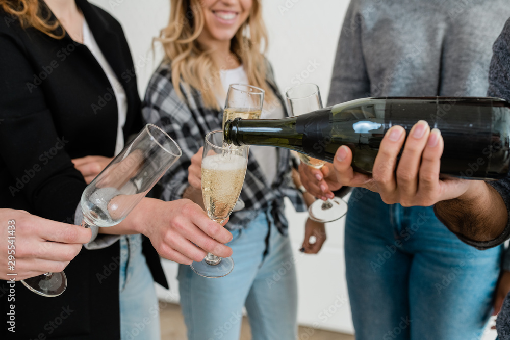 Young man with bottle of champagne pouring the dfrink into one of flutes Young man with bottle of champagne pouring the dfrink into one of flutes