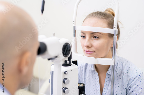 Young woman having her eyesight checked by special optometric equipment