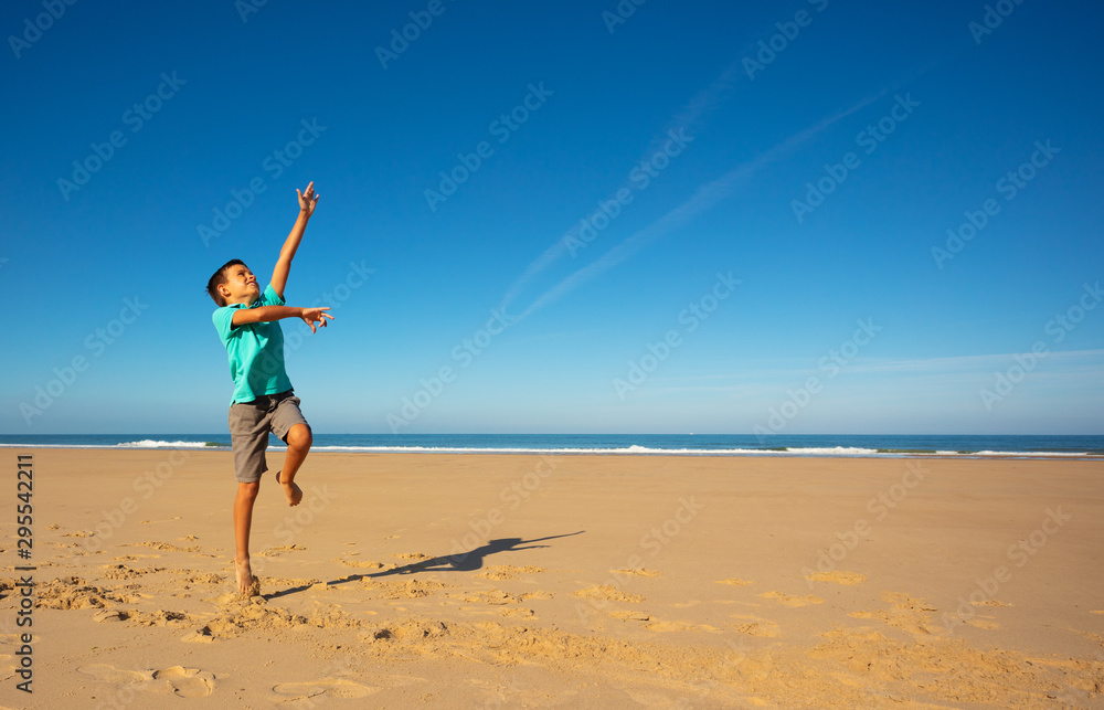 Little boy tries to jump high on the sand beach