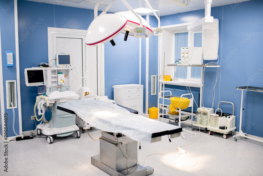 Operation table with large lamps above inside contemporary surgery room Operation table with large lamps above inside contemporary surgery room