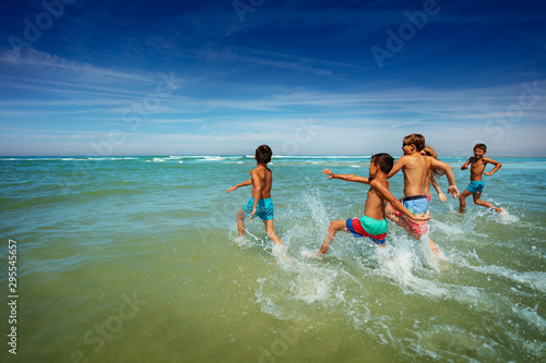Many boys and girls run to ocean waves on a beach