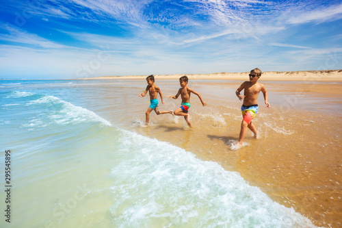 Group of little boys run to the sea on a beach