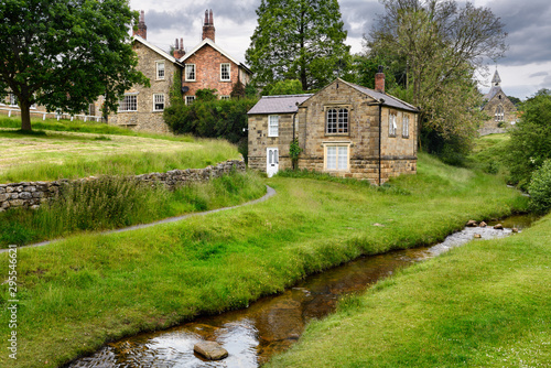 Hutton Beck flowing through Hutton-le-Hole village with stone houses on the village green North York Moors National Park England photo