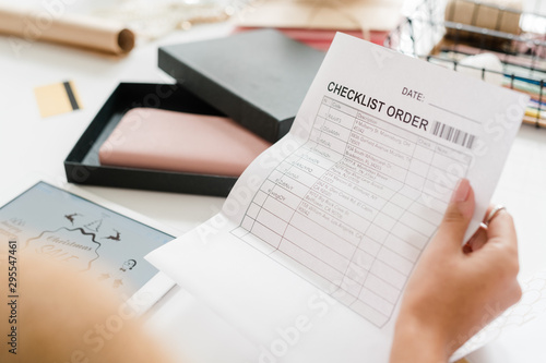 Paper with checklist order held by young female shopper looking through it