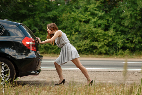 Photography Woman pushing broken car on road, breakdown