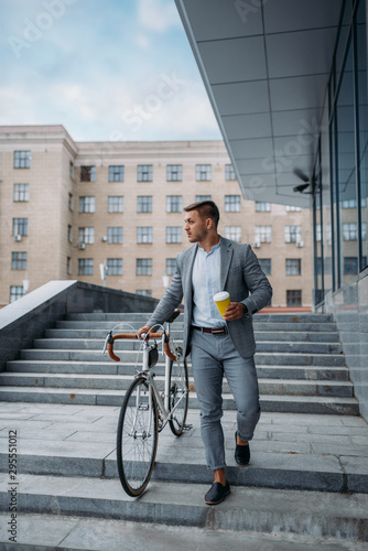 Businessman with bicycle comes down the stairs