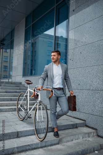 Fototapeta Naklejka Na Ścianę i Meble -  Businessman with bicycle comes down the stairs
