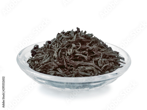 Leaves of black tea in glass oval bowl closeup isolated on white background                               