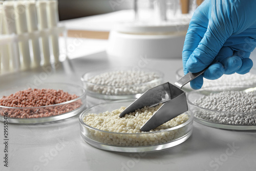 Scientist taking mineral fertilizer with scoop at table, closeup. Laboratory analysis photo