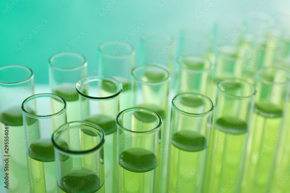 Many test tubes with liquid on color background, closeup Many test tubes with liquid on color background, closeup