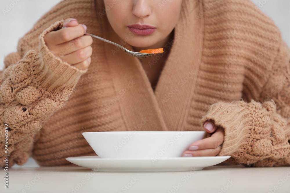 Sick young woman eating soup to cure flu, closeup Sick young woman eating soup to cure flu, closeup