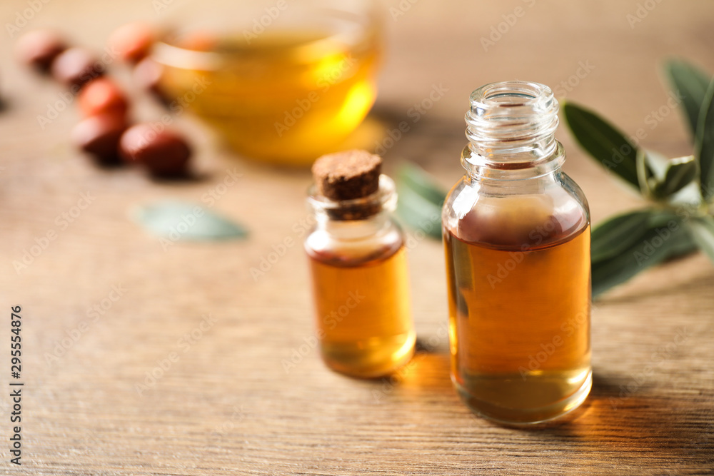 Glass bottles with jojoba oil on wooden table. Space for text Glass bottles with jojoba oil on wooden table. Space for text