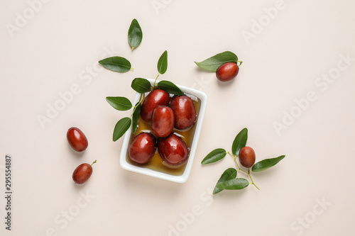 Sauce boat with jojoba oil and seeds on light background, flat lay photo