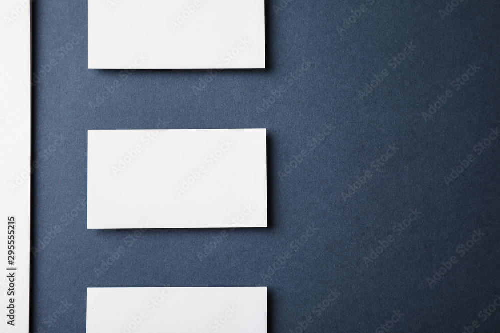 Blank business cards and paper sheet on dark grey background, flat lay. Mock up for design Blank business cards and paper sheet on dark grey background, flat lay. Mock up for design