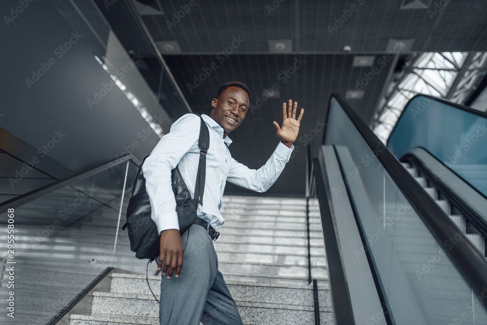 Ebony businessman going up the escalator in mall Ebony businessman going up the escalator in mall