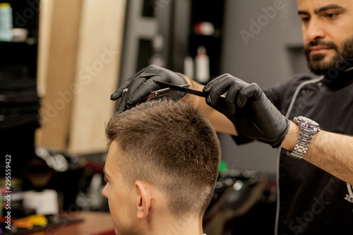 Brutal guy in modern Barber Shop. Hairdresser makes hairstyle a man . Master hairdresser does hairstyle with hair clipper. Concept barbershop