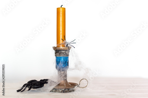 Candle with cobwebs and spiders on white background with copy space. Halloween concept photo