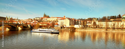 Prague cityscape in golden light in Autumn. View on St. Vitus Cathedral and Prague Castle across Vltava river with passenger ship in Fall, panoramic image composition.