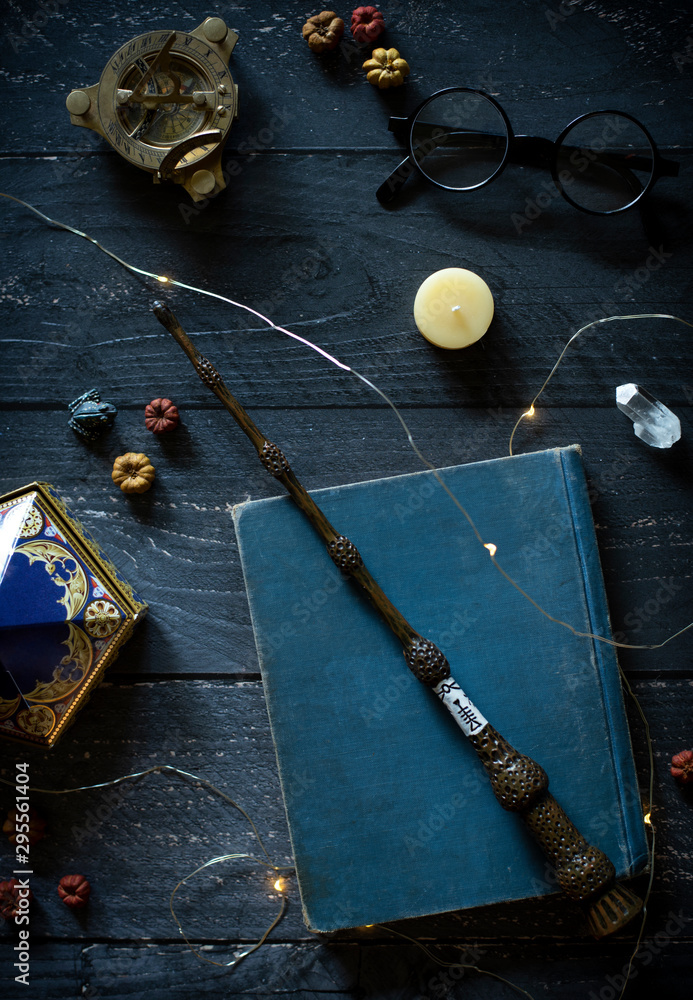 Naklejka premium magic wand and spell books on desk with glasses and other witch items, wizards desk, halloween theme, vintage books